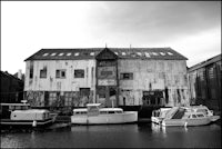 a black and white photo of boats docked in front of an old building